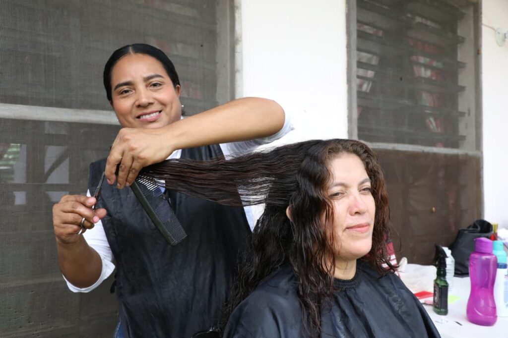 Una estilista corta el cabello a una mujer durante la jornada de atención del Gobierno del Pueblo en Huimanguillo, donde se ofrecieron servicios gratuitos a las familias de la comunidad Las Flores.