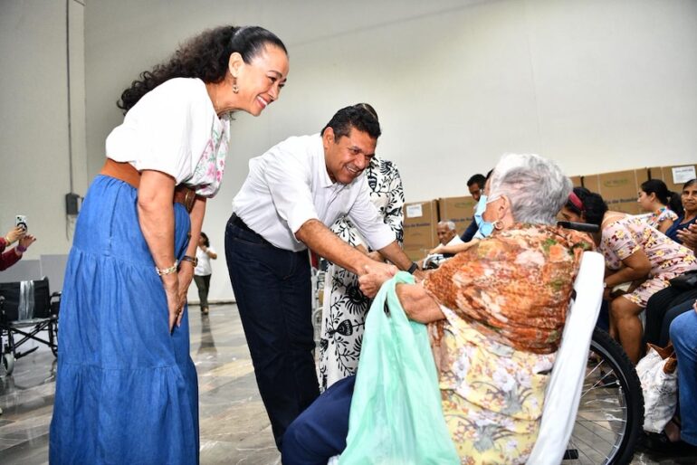Javier May y Aurora Raleigh saludan a una adulta mayor durante el acto de entrega.