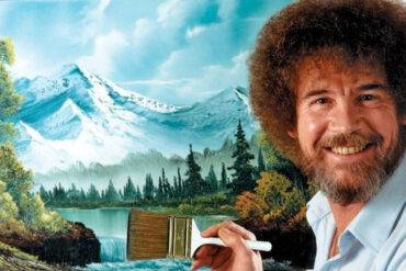 Bob Ross pintando un paisaje con "árboles felices" durante su programa, antes de la subasta de sus cuadros originales.