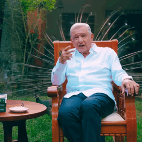 Andrés Manuel López Obrador durante el mensaje difundido desde su quinta en Palenque, sentado frente a una mesa de madera y una fotografía familiar.