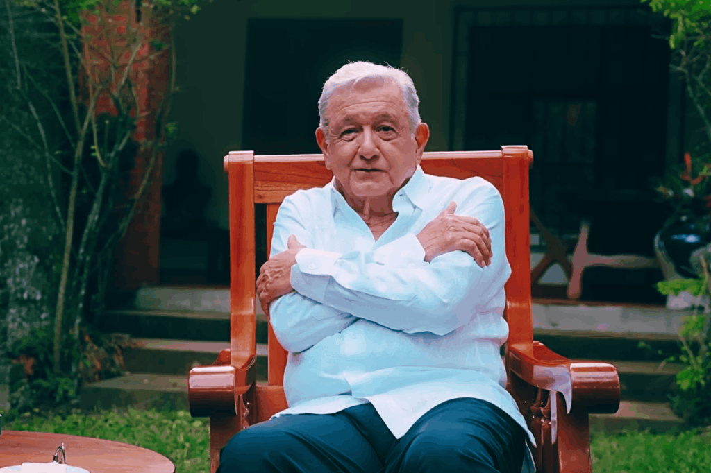 Andrés Manuel López Obrador sentado en un sillón de madera en su jardín en Palenque, con los brazos cruzados mientras dirige un mensaje grabado.