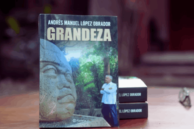 Andrés Manuel López Obrador sostiene un ejemplar de su libro Grandeza durante su presentación en Palenque.