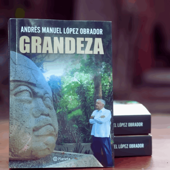 Andrés Manuel López Obrador sostiene un ejemplar de su libro Grandeza durante su presentación en Palenque.