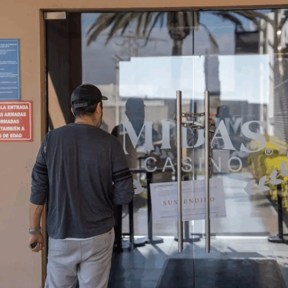 Hombre observa la puerta clausurada del casino Midas con aviso de suspensión visible.