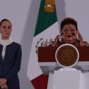 Claudia Sheinbaum observa mientras Ernestina Godoy habla en el podio presidencial durante anuncio en Palacio Nacional.