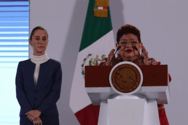 Claudia Sheinbaum observa mientras Ernestina Godoy habla en el podio presidencial durante anuncio en Palacio Nacional.