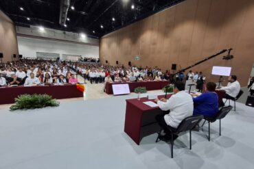 Personas participantes en el foro se saludan y dialogan en un ambiente cordial dentro del recinto.