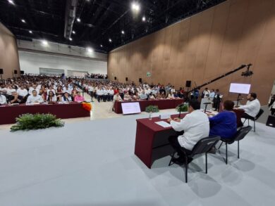 Personas participantes en el foro se saludan y dialogan en un ambiente cordial dentro del recinto.