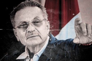 Retrato de Octavio Romero Oropeza en acto público, rostro serio, fondo institucional difuso.