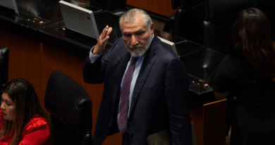 Legislador de traje oscuro gesticula durante una sesión en el pleno del Senado, rodeado de curules y asistentes.
