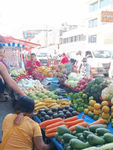 Puestos ambulantes de frutas y verduras instalados sobre la vía pública en los alrededores del mercado Pino Suárez, donde comerciantes atienden a compradores en un pasillo reducido entre mercancía y tráfico urbano.