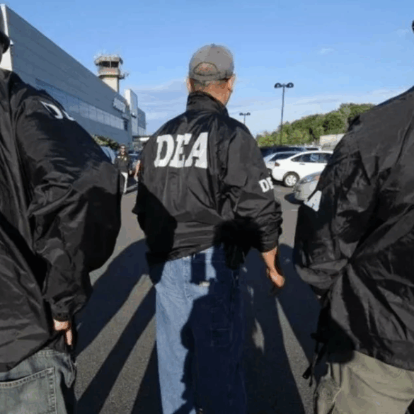 Agentes de la DEA con chamarras identificadas caminan en formación afuera de un edificio federal y un estacionamiento.