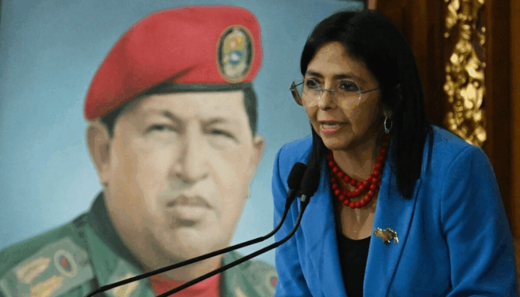 Delcy Rodríguez pronuncia un mensaje público tras ser designada presidenta encargada de Venezuela, con una imagen de Hugo Chávez al fondo.