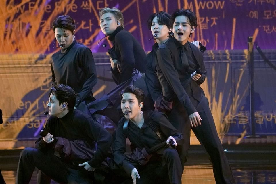 BTS durante una coreografía en concierto con luces y escenografía masiva