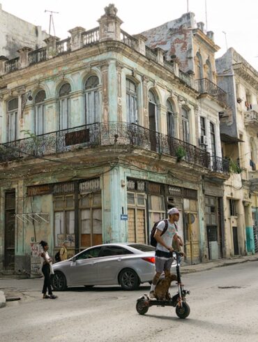 Calle del centro de La Habana con edificios antiguos deteriorados, poco tránsito y transporte público.