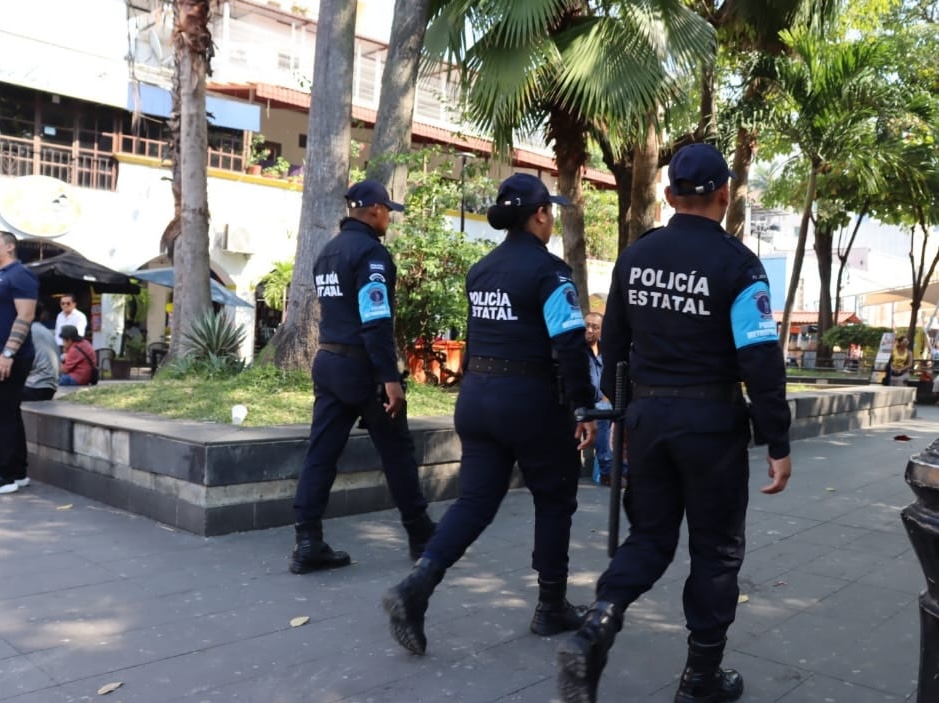 Tres elementos de la Policía Estatal de Tabasco patrullan a pie una zona peatonal arbolada, en operativo de vigilancia y proximidad dentro del nuevo esquema de seguridad metropolitana.