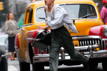 Timothée Chalamet corre despreocupado por una calle de Nueva York en una escena de Marty Supreme, caracterizado como Marty Mauser, con camisa abierta, lentes y un taxi amarillo detrás de él.