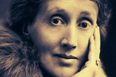 Primer plano del rostro de Virginia Woolf en edad adulta, con la mano apoyada en la mejilla y expresión contemplativa.