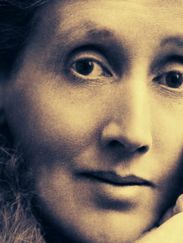 Primer plano del rostro de Virginia Woolf en edad adulta, con la mano apoyada en la mejilla y expresión contemplativa.