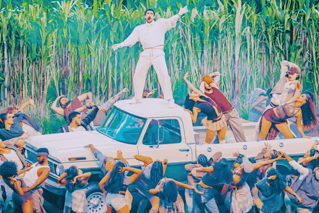 Bad Bunny canta sobre camioneta rodeado de bailarines; fondo de cañaverales.