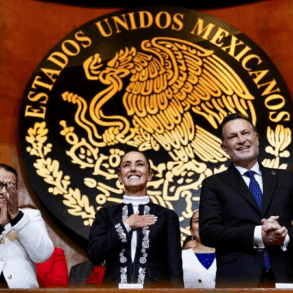 Claudia Sheinbaum junto a integrantes del gabinete y autoridades federales aplauden frente al escudo nacional durante el acto oficial.