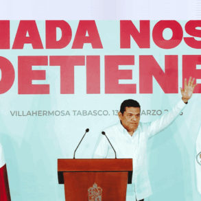El gobernador Javier May Rodríguez levanta la mano durante su informe trimestral en Villahermosa, frente al mensaje “Nada nos detiene”.