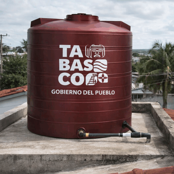 Tinaco color vino de 450 litros con logotipo del Gobierno de Tabasco instalado en la azotea de una vivienda, con tubería conectada y vista urbana al fondo en Villahermosa.