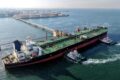 Buque petrolero guiado por remolcadores hacia terminal de carga de crudo, símbolo del comercio de hidrocarburos que depende del estrecho de Ormuz