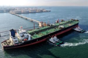 Buque petrolero guiado por remolcadores hacia terminal de carga de crudo, símbolo del comercio de hidrocarburos que depende del estrecho de Ormuz