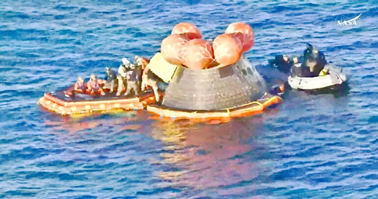 La cápsula Orión de la misión Artemis II flotando en el océano Pacífico rodeada de botes y personal de rescate tras el amerizaje frente a San Diego