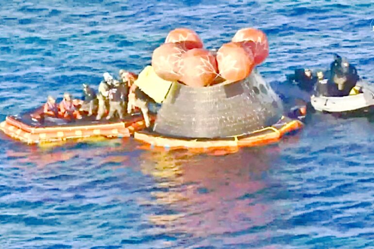 La cápsula Orión de la misión Artemis II flotando en el océano Pacífico rodeada de botes y personal de rescate tras el amerizaje frente a San Diego