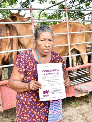 Beneficiaria del programa Crédito Ganadero a la Palabra sostiene su constancia de aprobación frente a un camión con novillonas en Huimanguillo, Tabasco