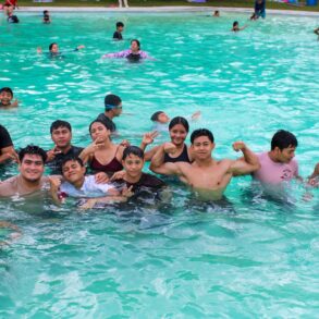 Grupo de jóvenes y familias conviviendo dentro de una alberca pública en la Ciudad Deportiva de Villahermosa durante el cierre de vacaciones