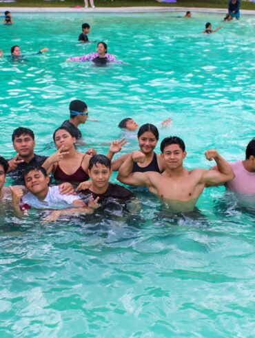 Grupo de jóvenes y familias conviviendo dentro de una alberca pública en la Ciudad Deportiva de Villahermosa durante el cierre de vacaciones