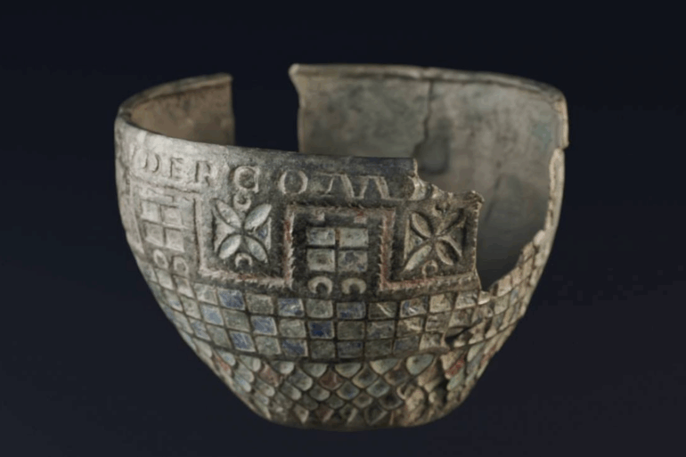 Copa de Berlanga, cuenco romano de bronce fragmentado con decoración esmaltada geométrica, fotografiada sobre fondo negro