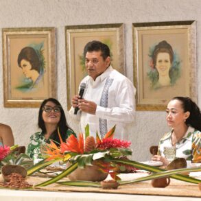 Gobernador Javier May Rodríguez habla ante las embajadoras de la Feria Tabasco 2026 en el Salón de las Flores, con retratos de Flores de Oro anteriores al fondo.