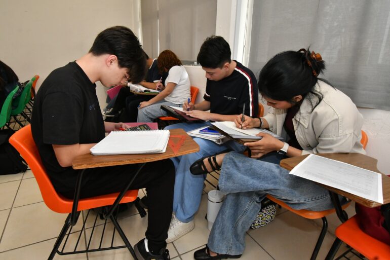 Estudiantes universitarios realizan ejercicios académicos en aula durante proceso de preparación académica