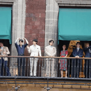 Integrantes de BTS saludan desde un balcón de Palacio Nacional junto a Claudia Sheinbaum.