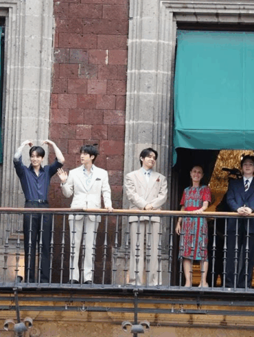 Integrantes de BTS saludan desde un balcón de Palacio Nacional junto a Claudia Sheinbaum.