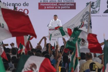 Gobernador Javier May Rodríguez en el podio de la rendición de cuentas de Claudia Sheinbaum en Plaza de Armas de Villahermosa, rodeado de banderas mexicanas