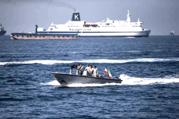 Militares iraníes armados a bordo de una lancha rápida patrullan el estrecho de Ormuz con la bandera de Irán visible