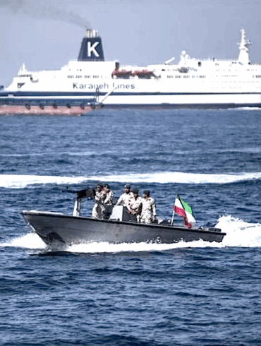 Militares iraníes armados a bordo de una lancha rápida patrullan el estrecho de Ormuz con la bandera de Irán visible
