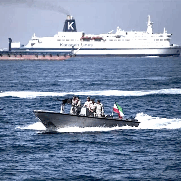 Militares iraníes armados a bordo de una lancha rápida patrullan el estrecho de Ormuz con la bandera de Irán visible