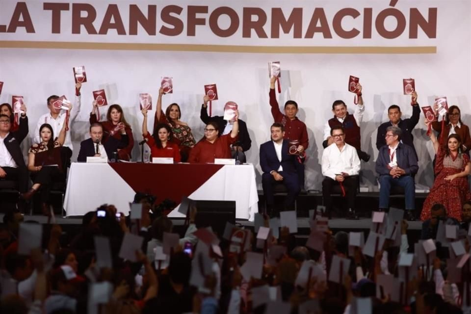 Miembros del presidium y militantes de Morena levantan libretas en señal de aprobación durante la votación unánime que designó a Ariadna Montiel como presidenta nacional del partido