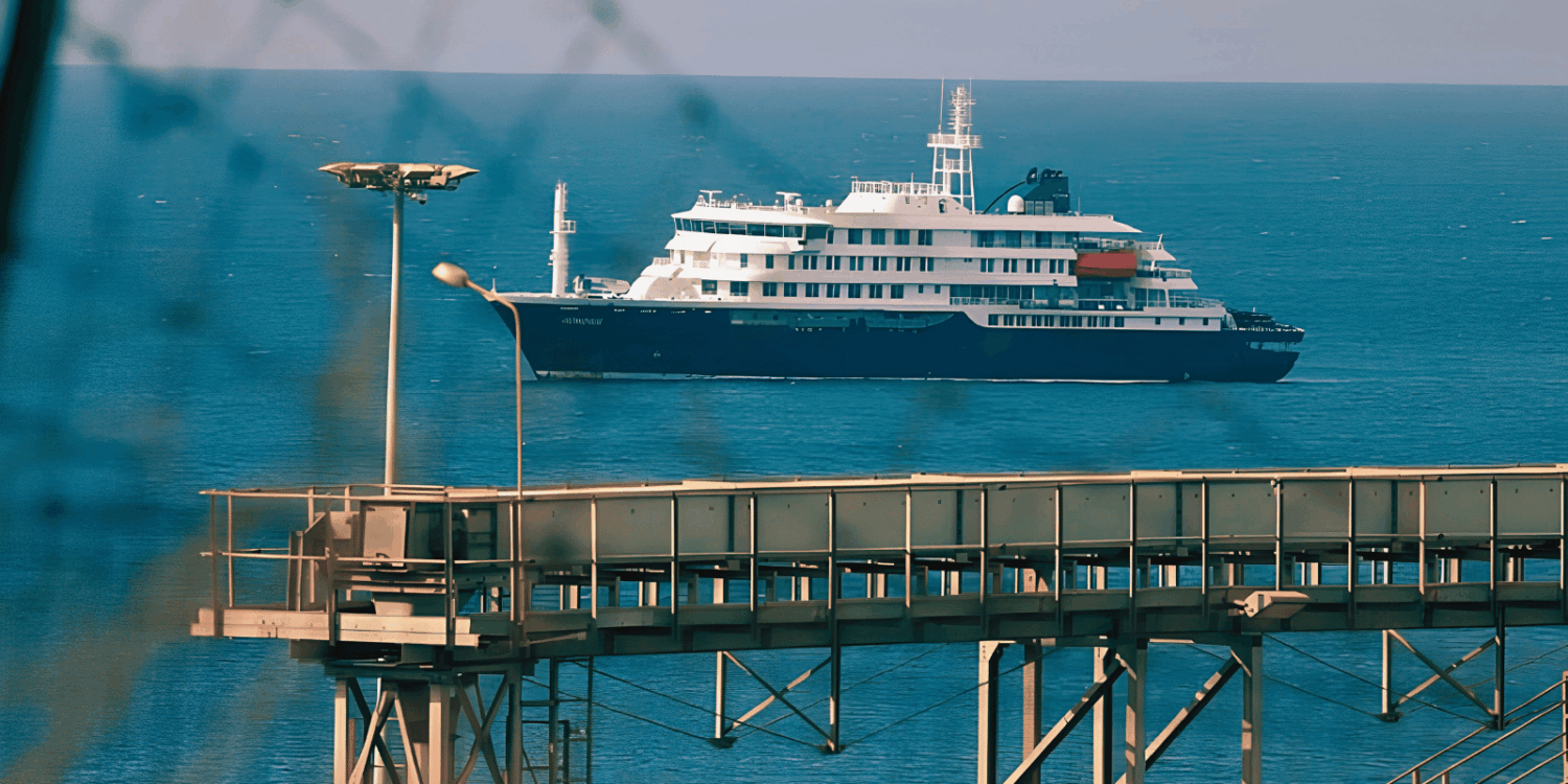 El crucero MV Hondius fondeado frente al puerto industrial de Granadilla en Tenerife, visto a través del alambrado del perímetro de seguridad sanitaria, este sábado previo al desembarco internacional.