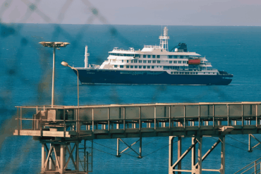 El crucero MV Hondius fondeado frente al puerto industrial de Granadilla en Tenerife, visto a través del alambrado del perímetro de seguridad sanitaria, este sábado previo al desembarco internacional.