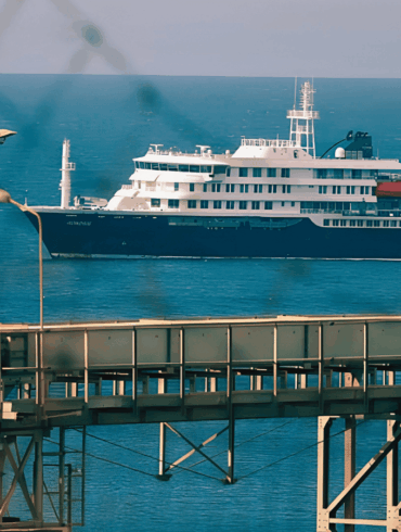 El crucero MV Hondius fondeado frente al puerto industrial de Granadilla en Tenerife, visto a través del alambrado del perímetro de seguridad sanitaria, este sábado previo al desembarco internacional.