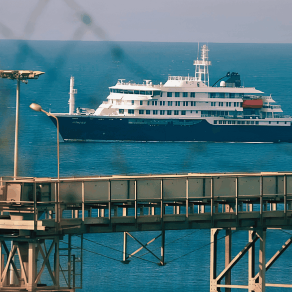 El crucero MV Hondius fondeado frente al puerto industrial de Granadilla en Tenerife, visto a través del alambrado del perímetro de seguridad sanitaria, este sábado previo al desembarco internacional.