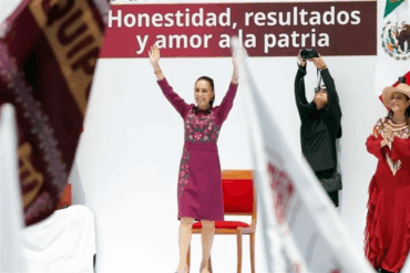 La presidenta Claudia Sheinbaum con los brazos en alto frente al lema Honestidad, resultados y amor a la patria durante su segundo informe de rendición de cuentas en el Monumento a la Revolución