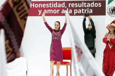 La presidenta Claudia Sheinbaum con los brazos en alto frente al lema Honestidad, resultados y amor a la patria durante su segundo informe de rendición de cuentas en el Monumento a la Revolución